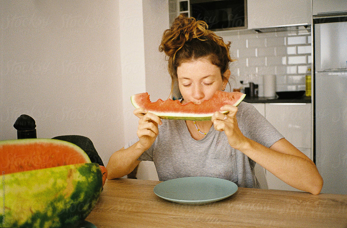 UGC portrait of young woman eating watermelon at home