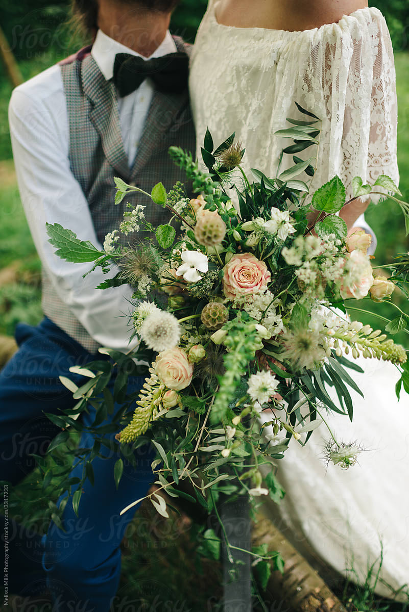 bride and groom holding a beautiful wild flower bouquet