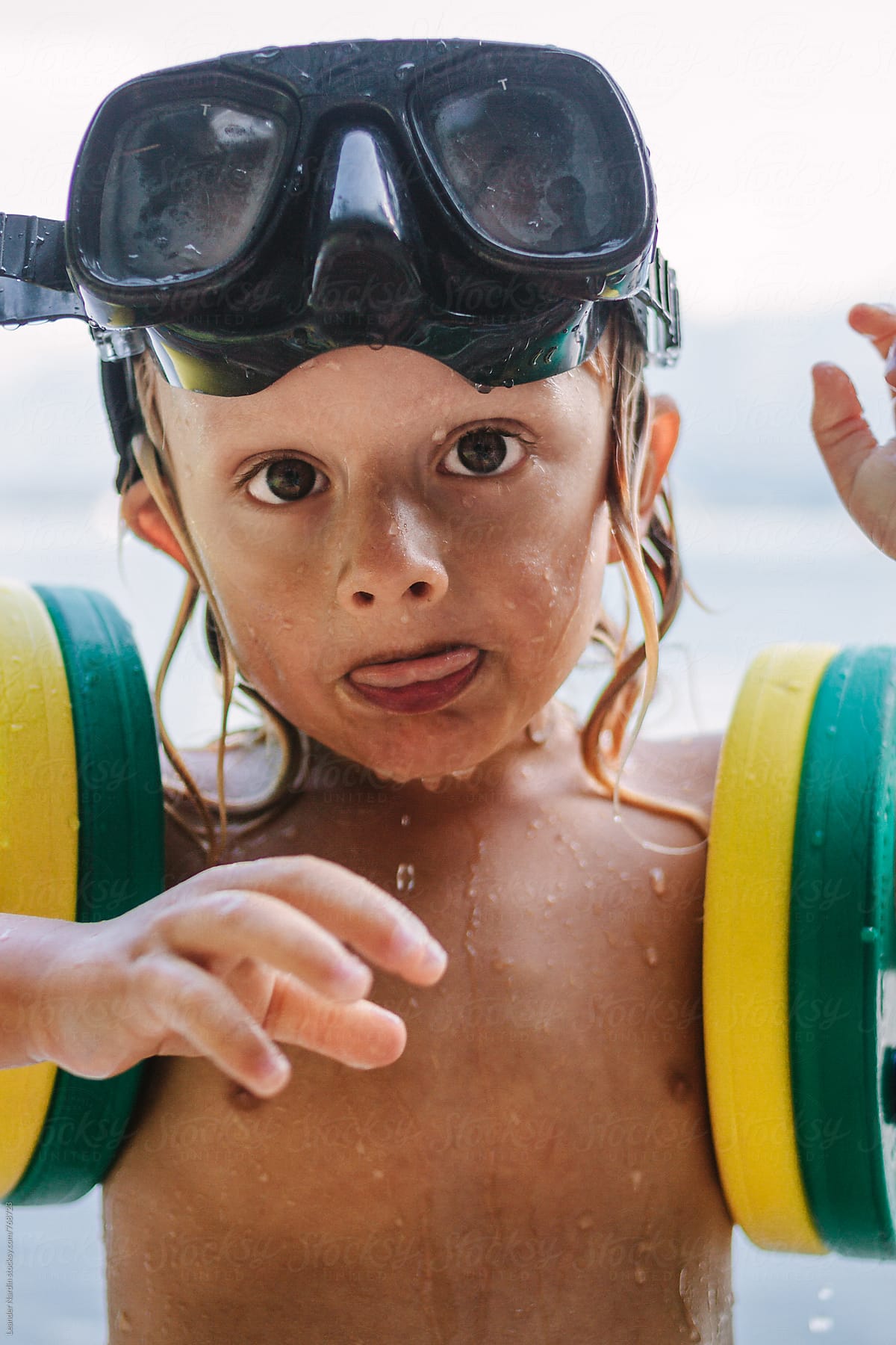 wet toddler with diving goggles on the head and swimming rings