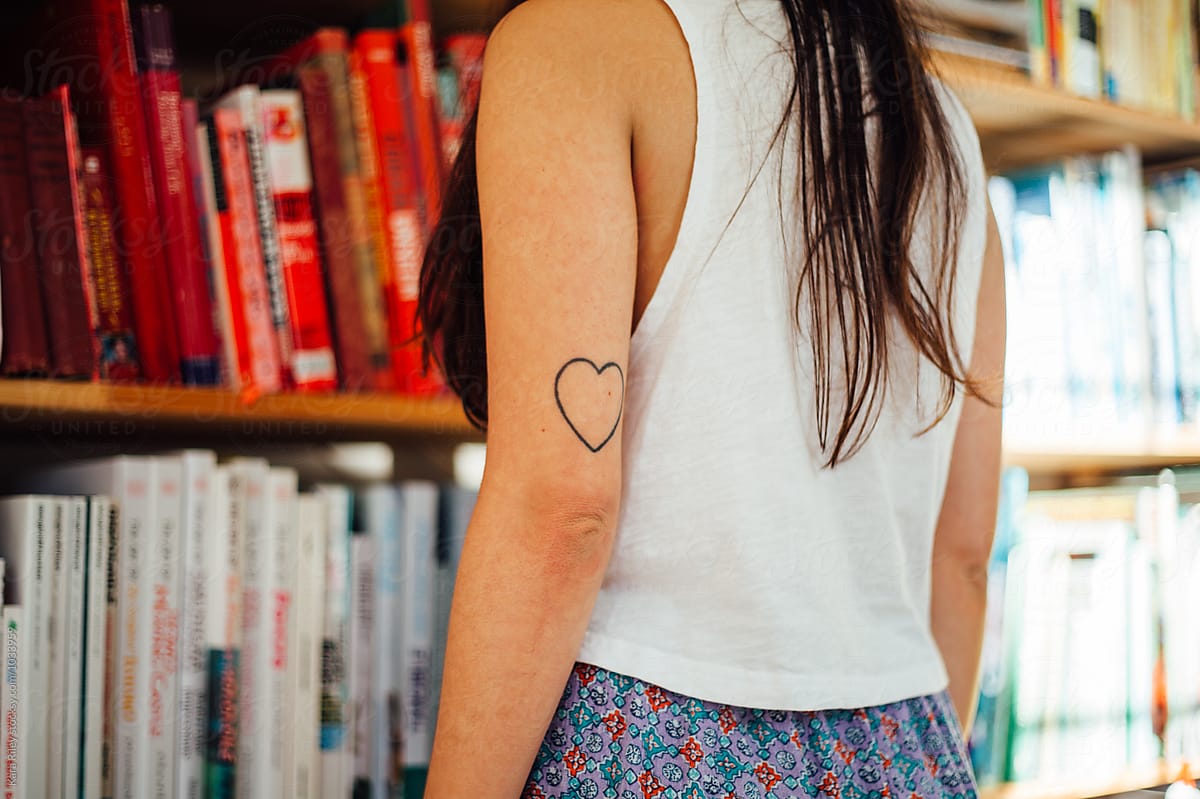 Woman with heart tattoo looking at bookshelf