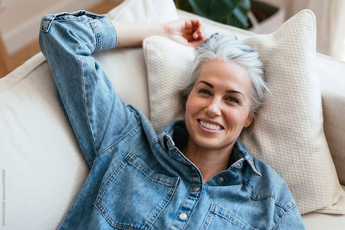 Cheerful middle aged woman resting on sofa