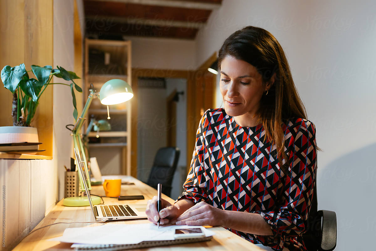 Adult woman making notes in home office