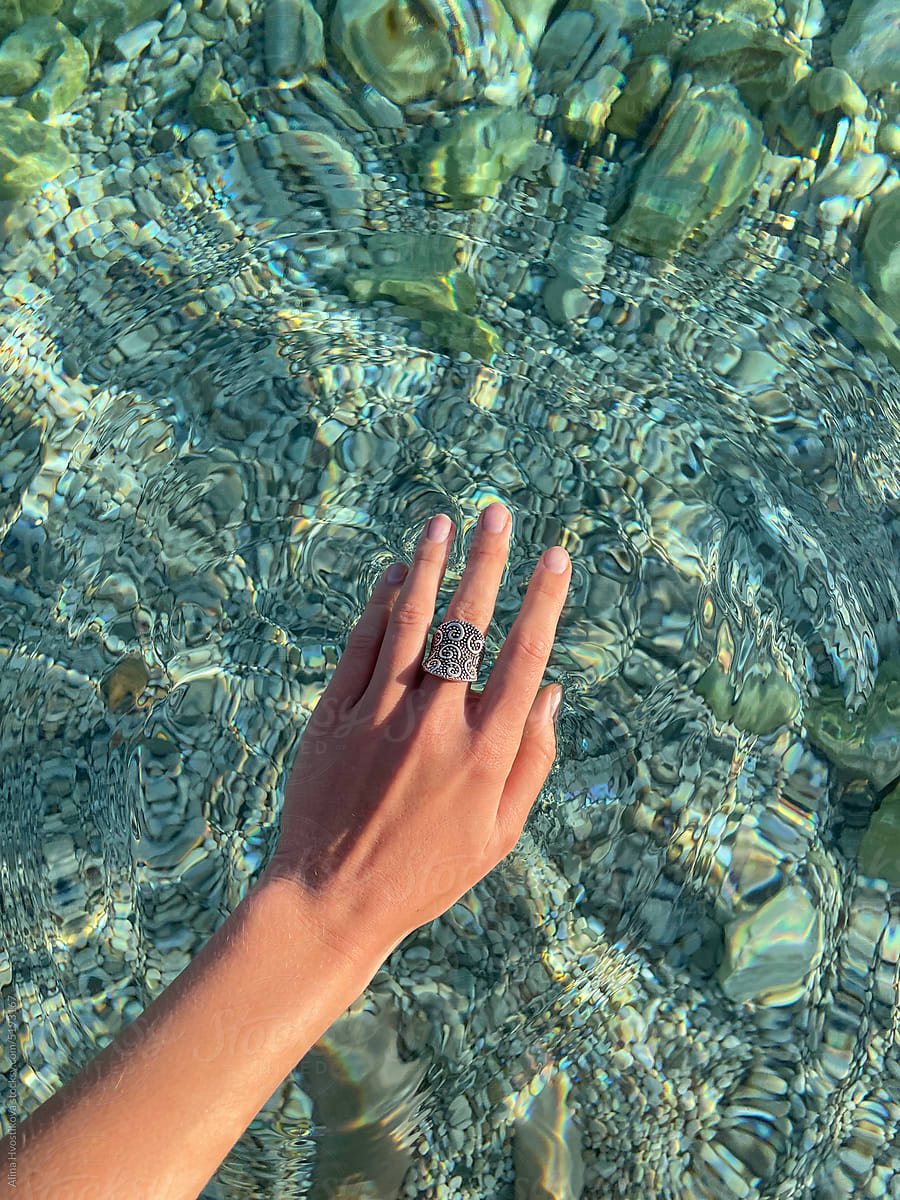 Crop female hand against transparent sea