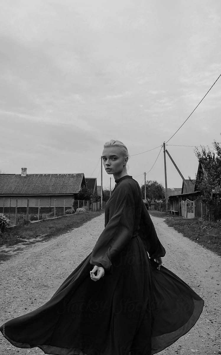 photo of a girl in a black dress that develops in the wind outside in the village