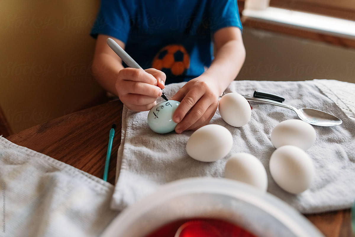 Child decorating Easter egg.
