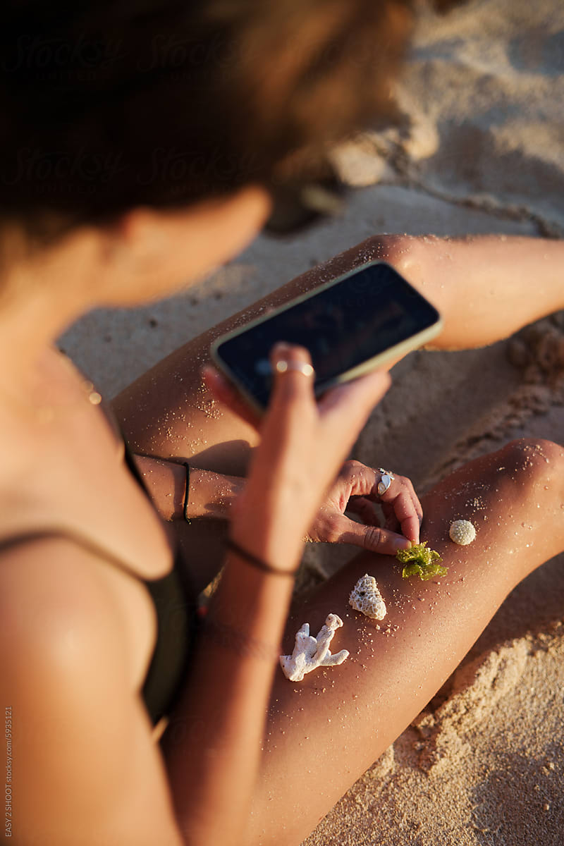 Woman Using Smartphone on Sandy Beach at Sunset