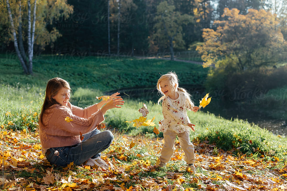Mother and daughter playing with autumn leaves