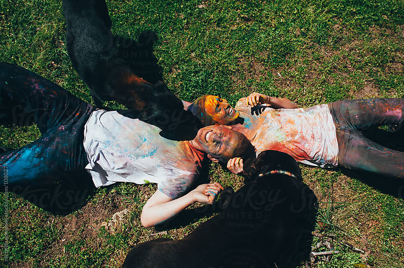Couple Laying in Grass with Dogs with Holi/Colored Powder