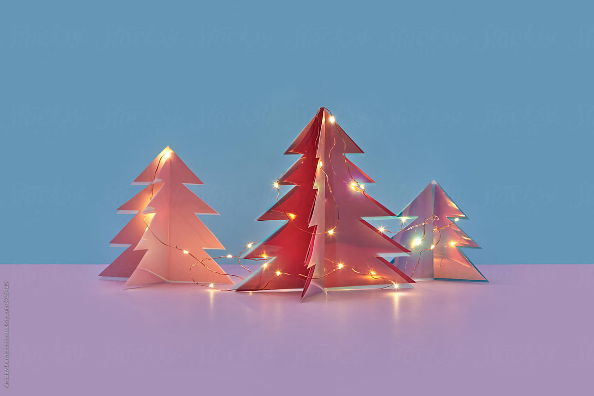 Glowing garlands decorating three Christmas trees in studio