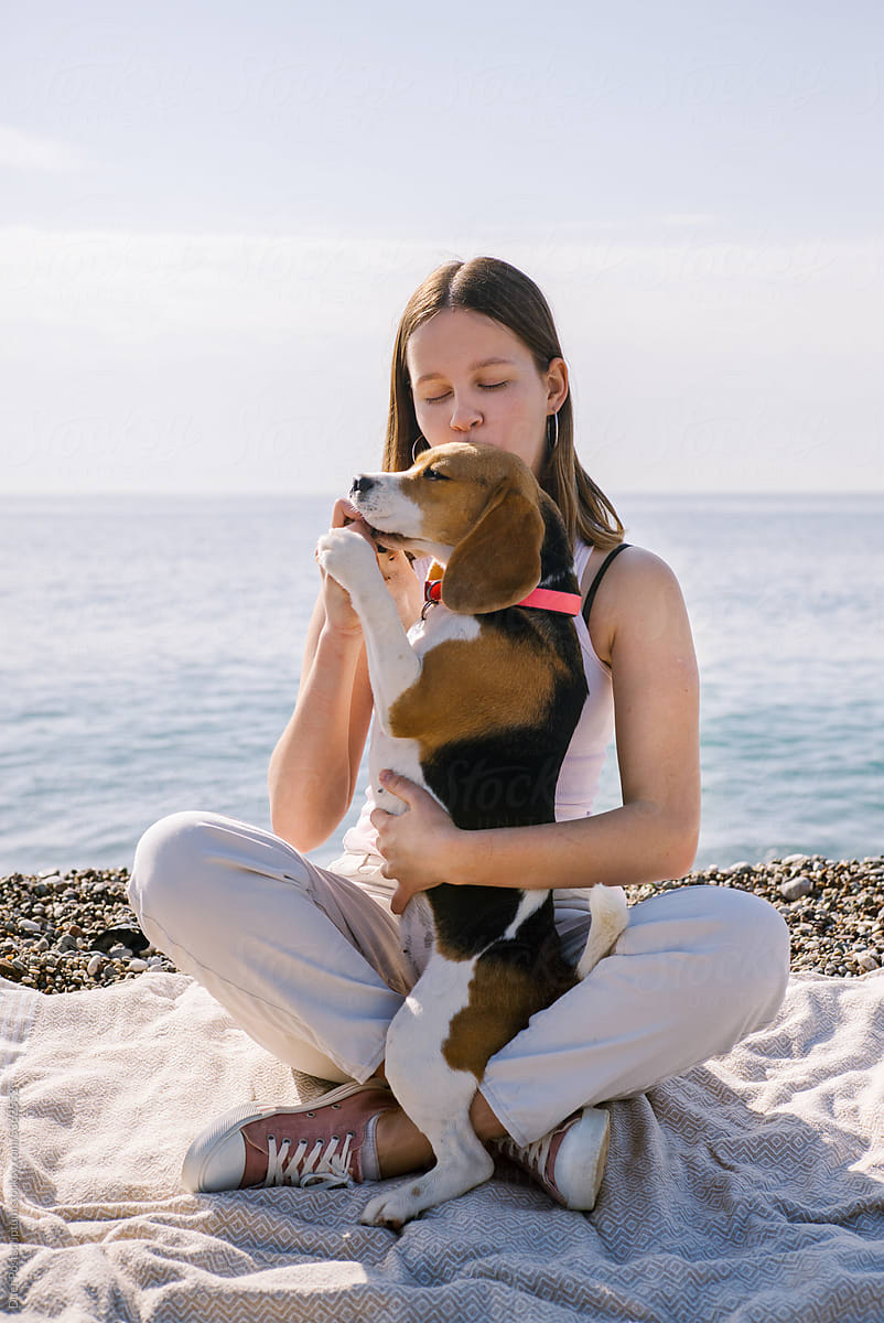 Young woman treats her dog to a tasty lump on the beach