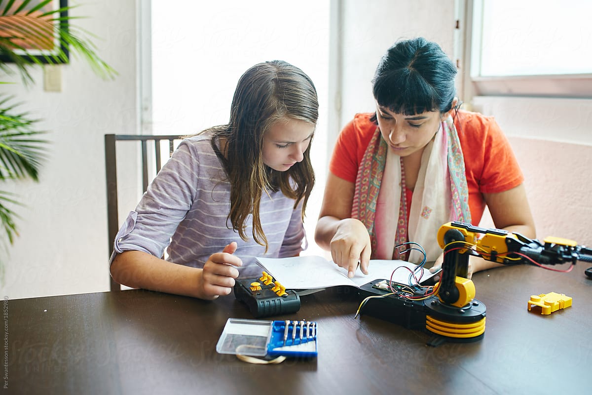 Adult with young student assembling a robotics kit