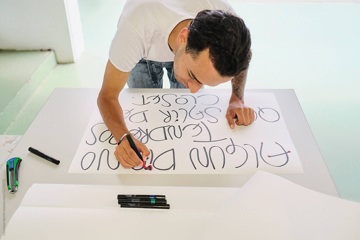 Gay man writes protest phrases in Spanish on a poster board
