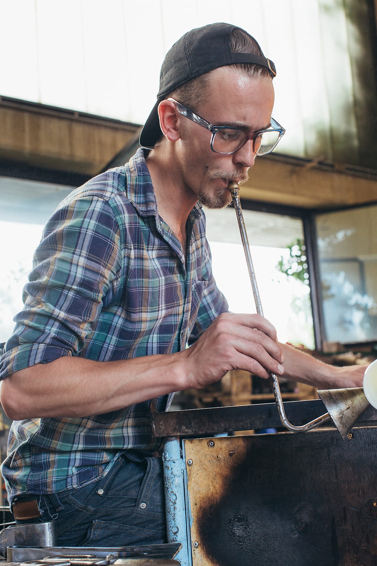 Artisan Glass Workshop - Portrait of Male Hipster Artist Blowing Glass