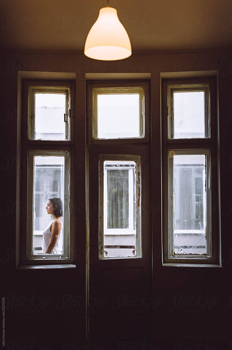 A beautiful girl standing  on the windowsill in the white room