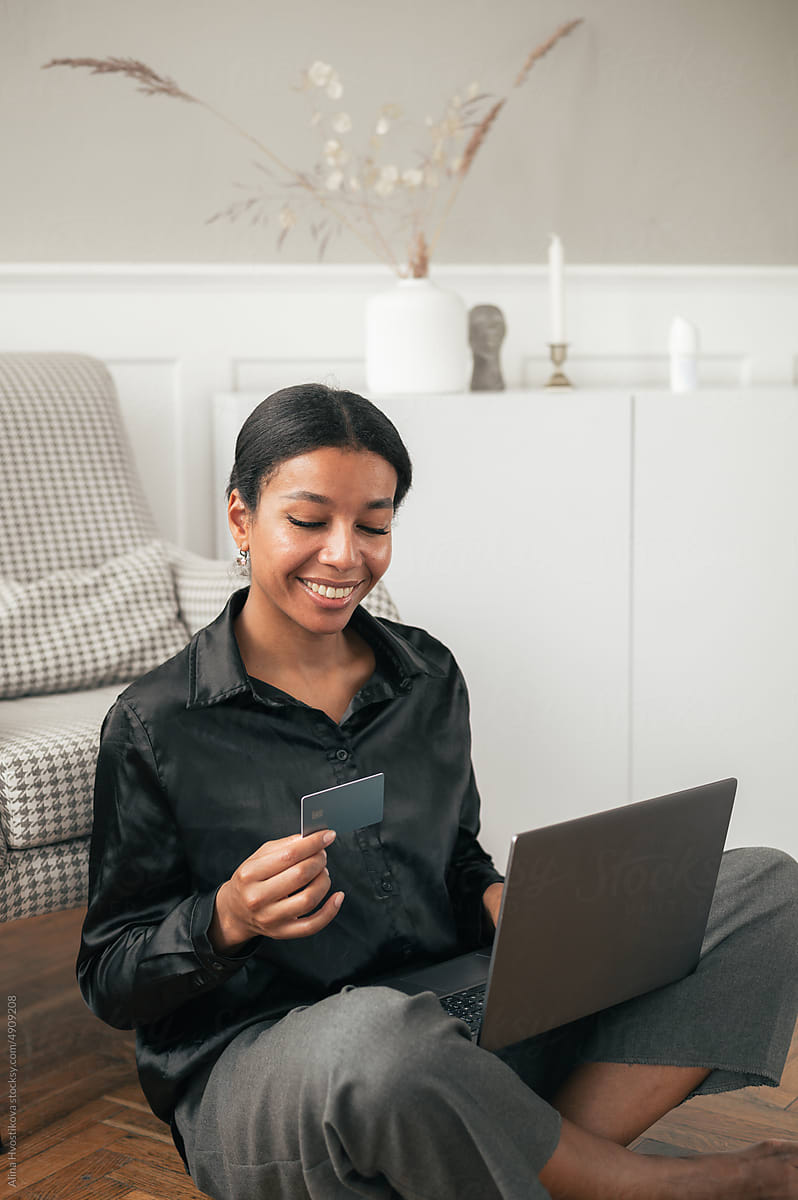 Smiling black woman with laptop and plastic card
