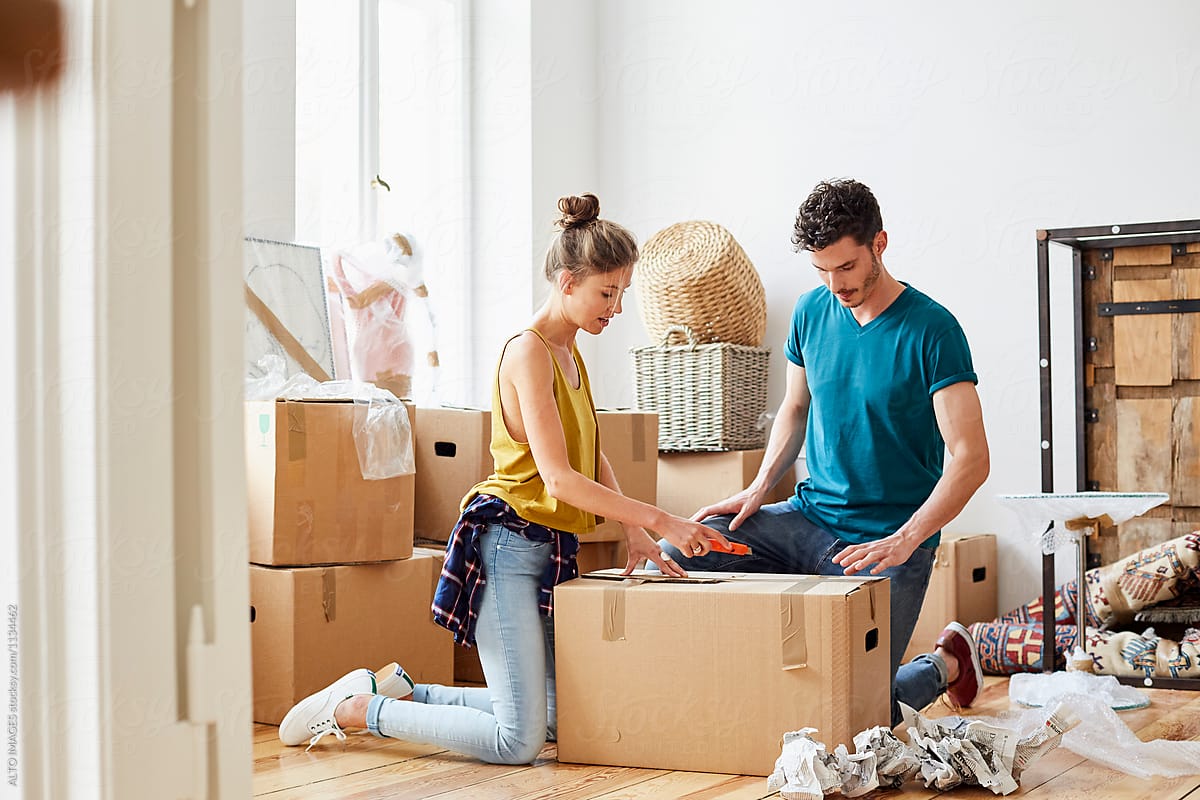 Couple Unpacking Cardboard Box In New House