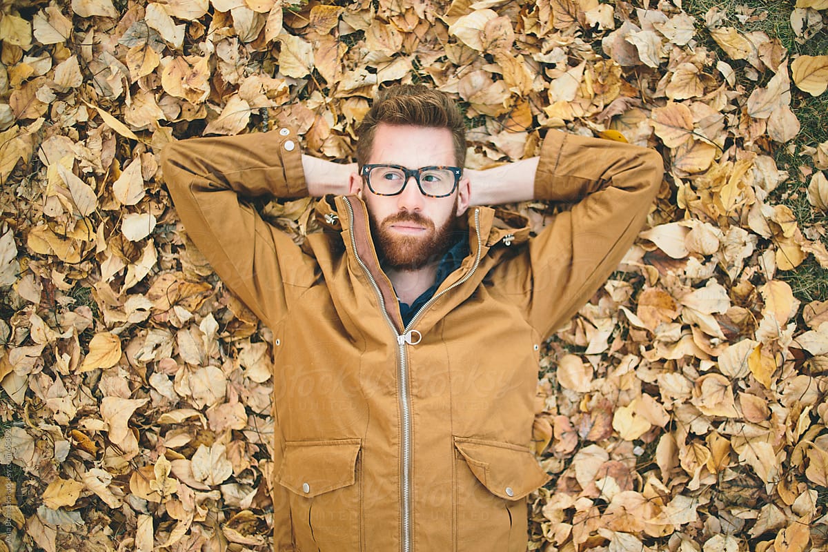Autumn: A man in glasses laying yellow and orange fall leaves
