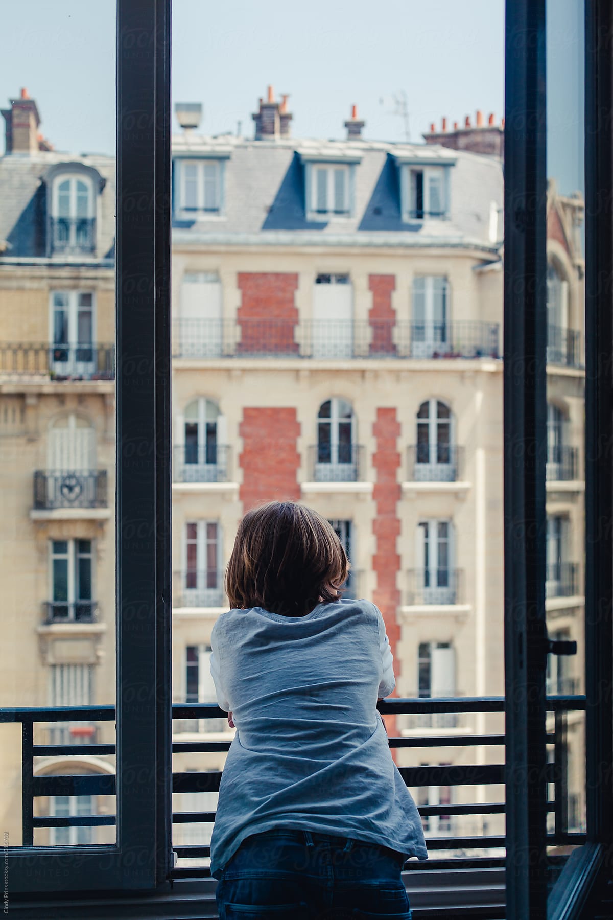 Boy leaning out of a window enjoying the view in Paris