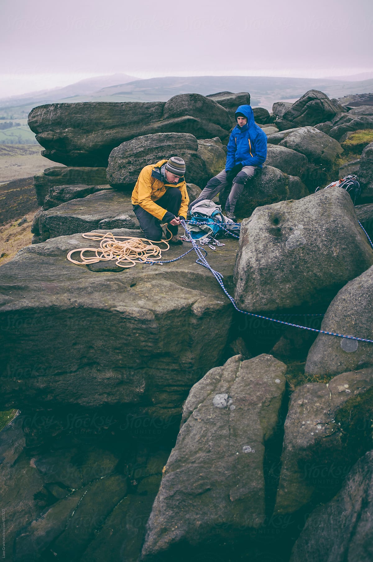 Two climbers setting up an anchor point for abseiling.