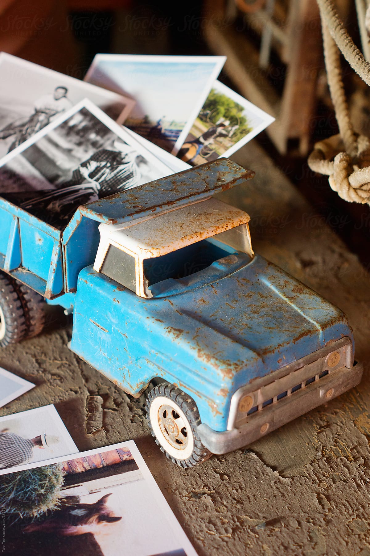 Printed images displayed in an old metal toy pickup on a rustic table