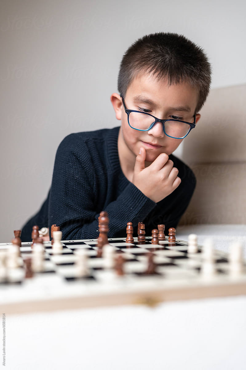 Kid thinking while playing chess.
