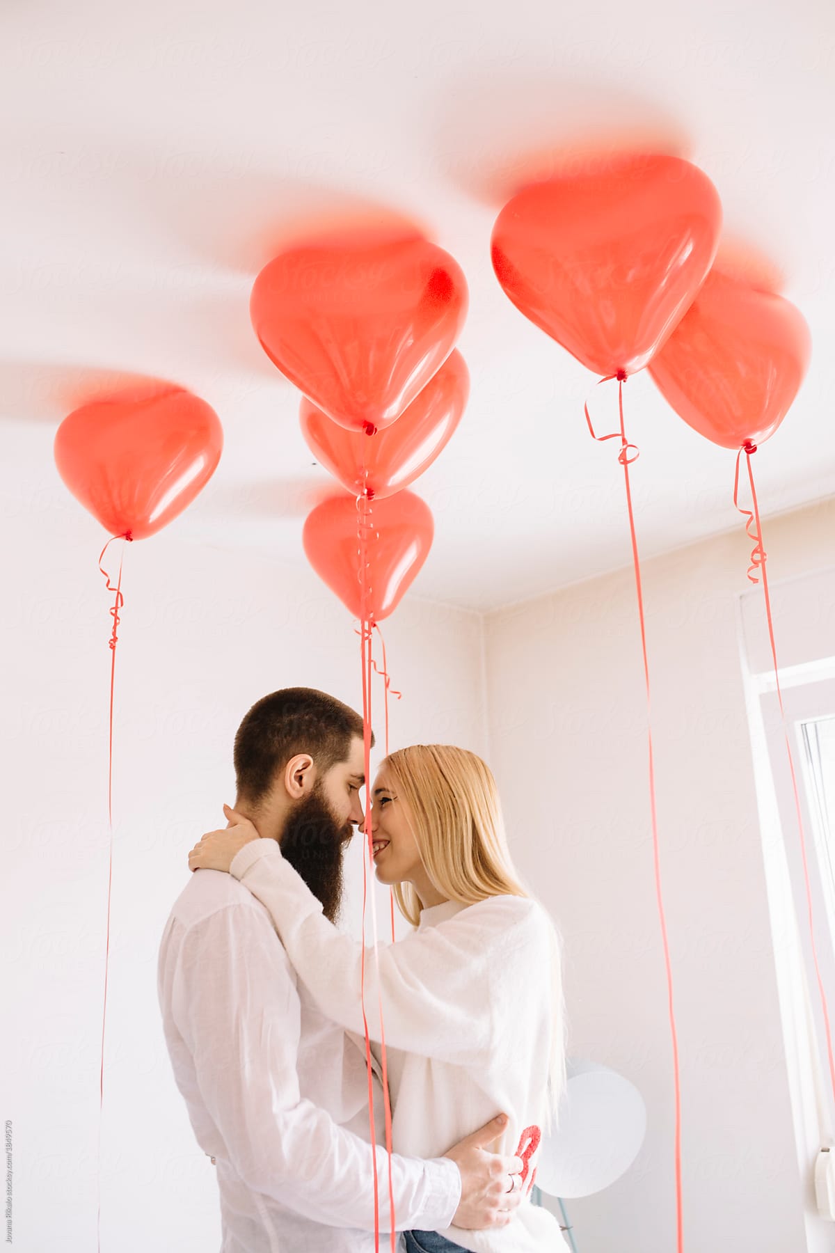 Young Couple Kissing And Hugging Under Red Balloons By Jovana Rikalo