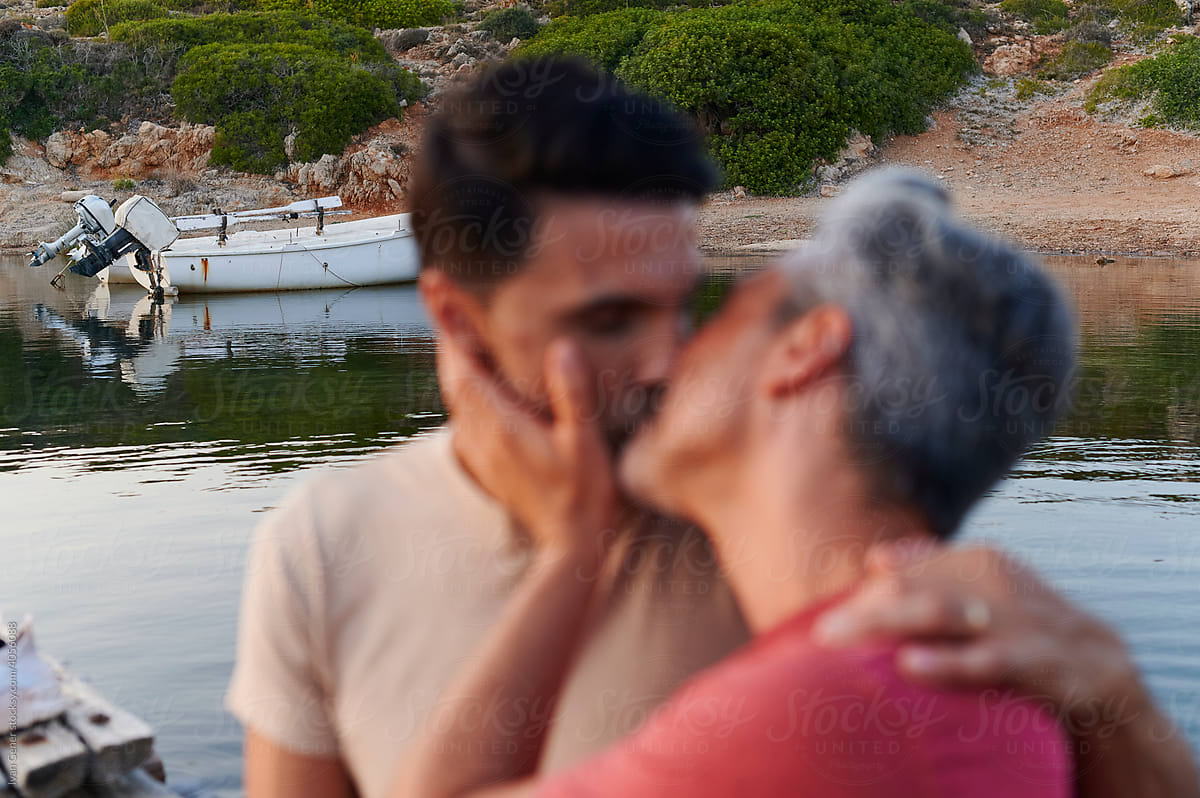 Loving gay couple kissing by a lake
