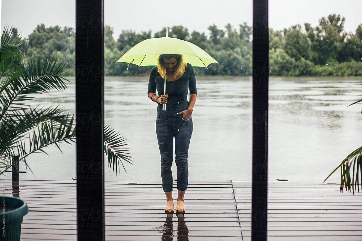 Barefoot Woman By The River On A Rainy Day By Stocksy Contributor
