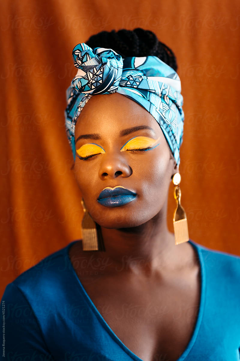Woman with African print head band and creative makeup over orange