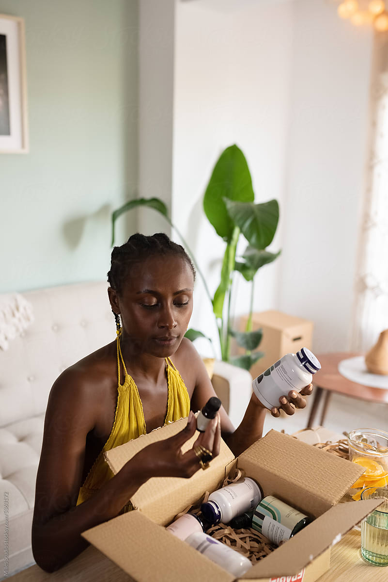 Black woman unpacking box with oils and vitamins