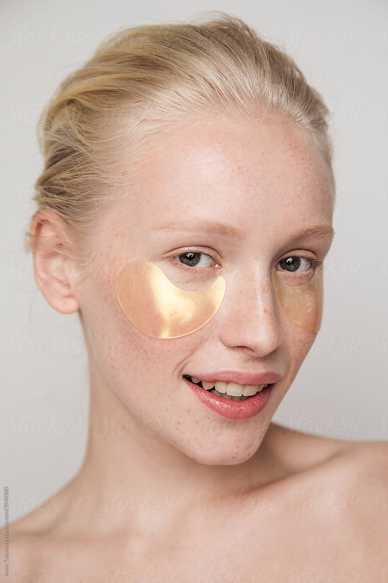 Young happy freckled model with golden under-eye patches