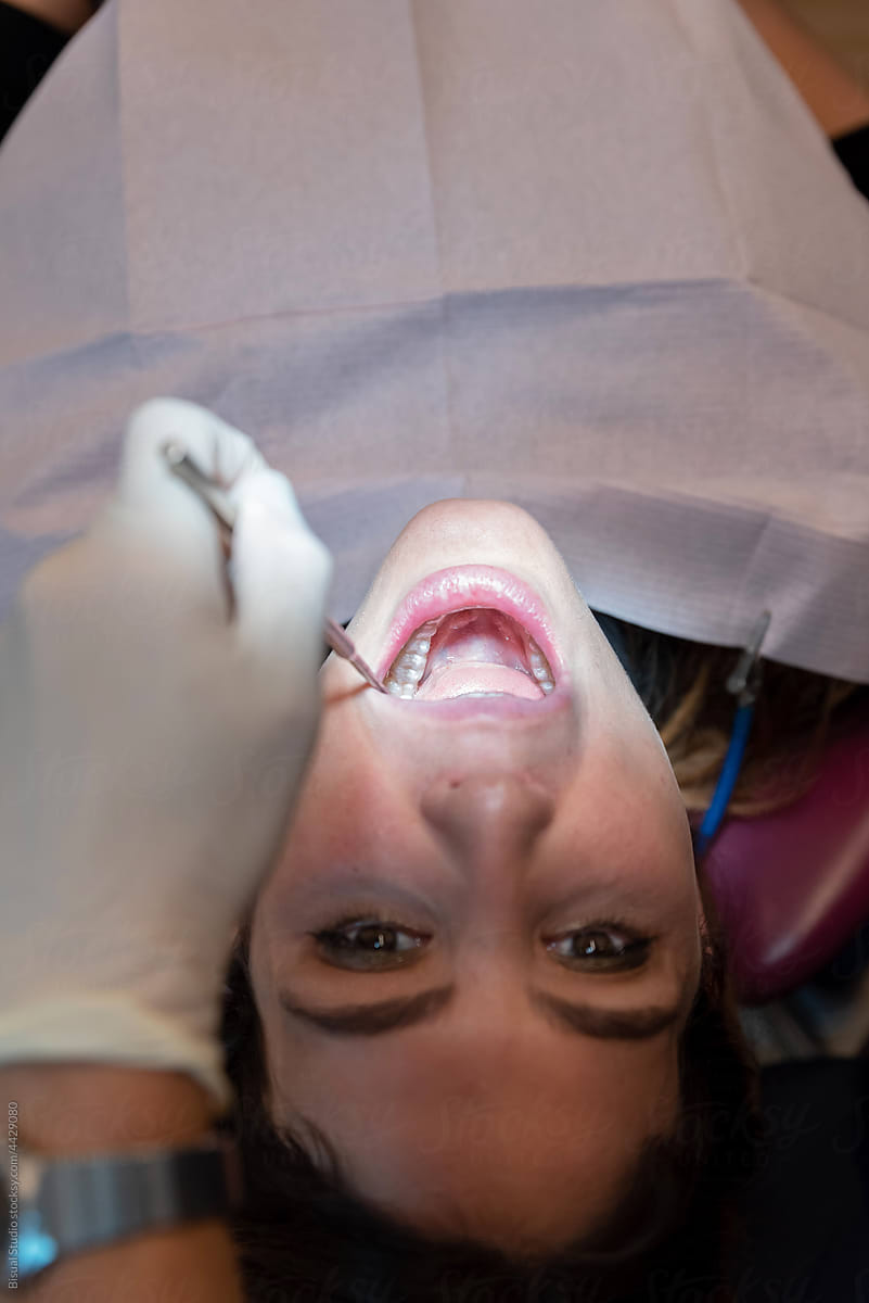 Faceless dentist examining invisible orthodontics of female patient