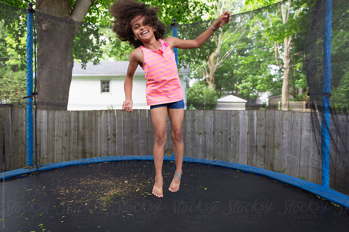 A young girl jumping in a large trampoline.