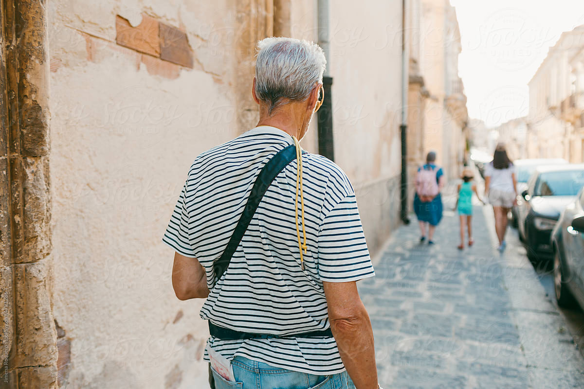 Back of senior man walking on the sidewalk of an old Italian City.