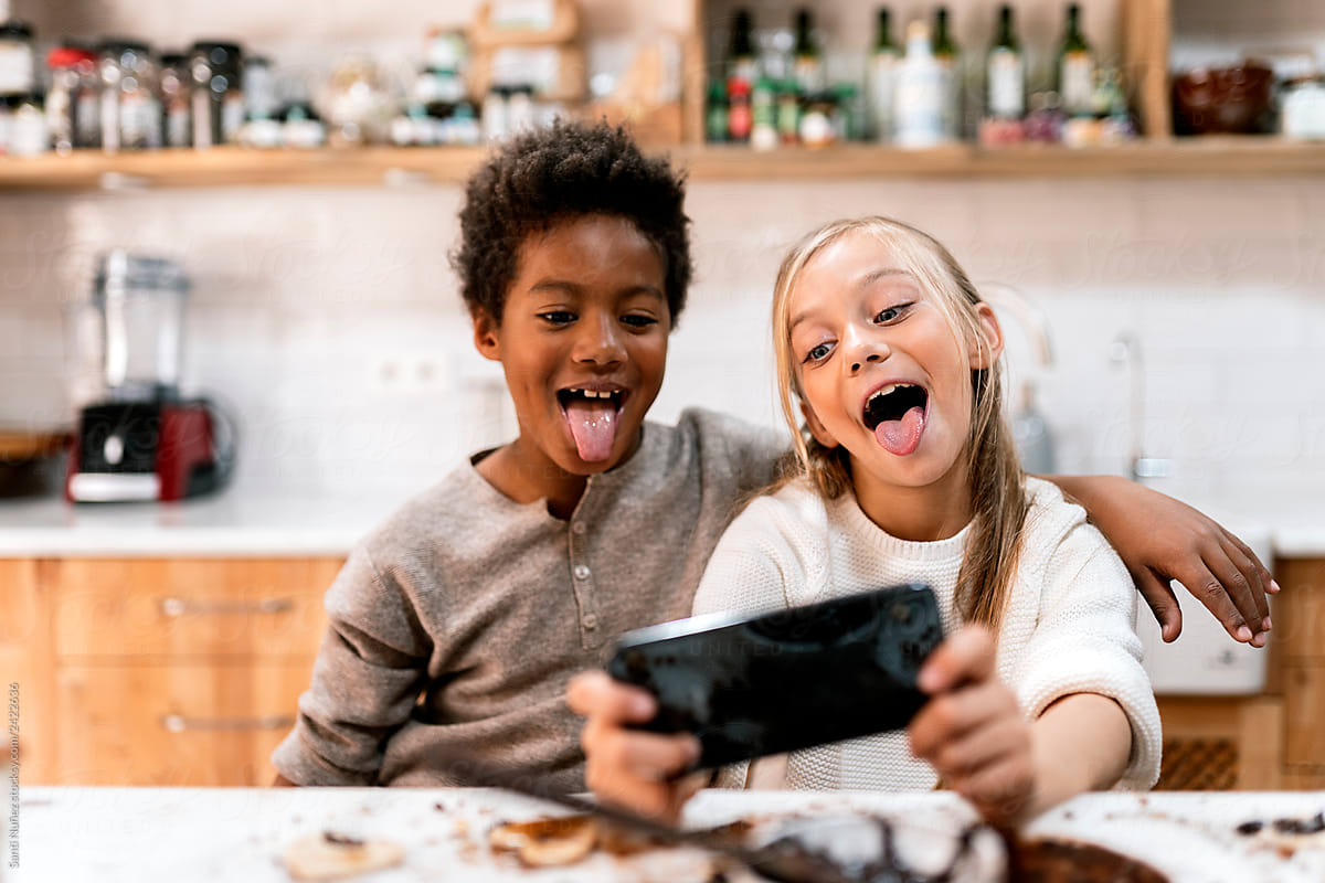 Children making faces with smartphone in kitchen