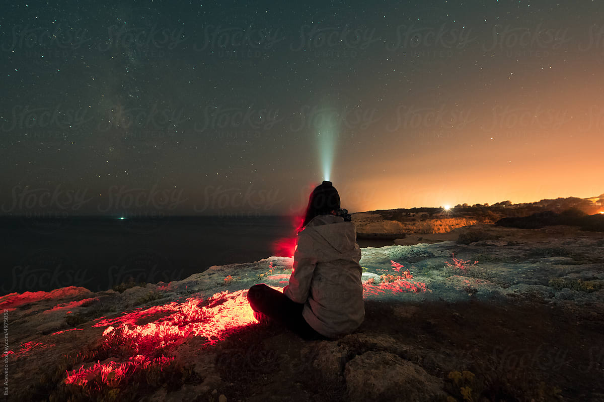 Woman looking at the night sky with head flashlight