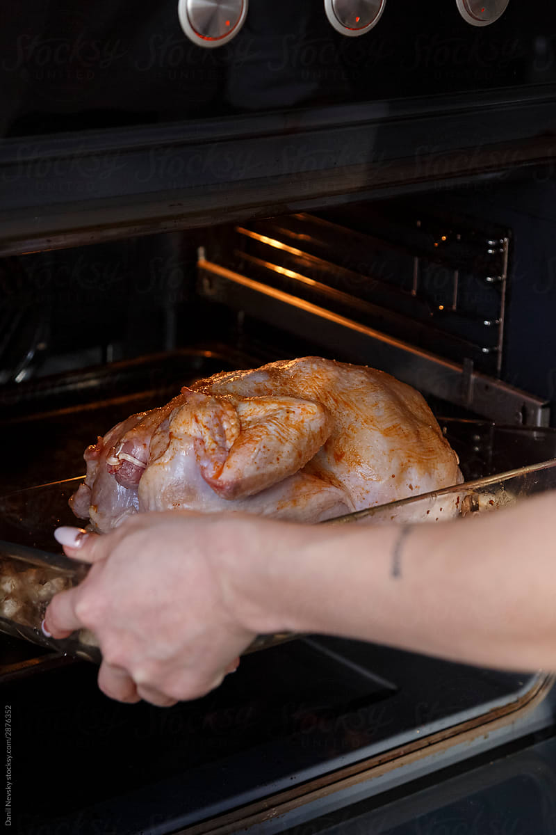 Cook placing seasoned chicken with vegetables in to oven
