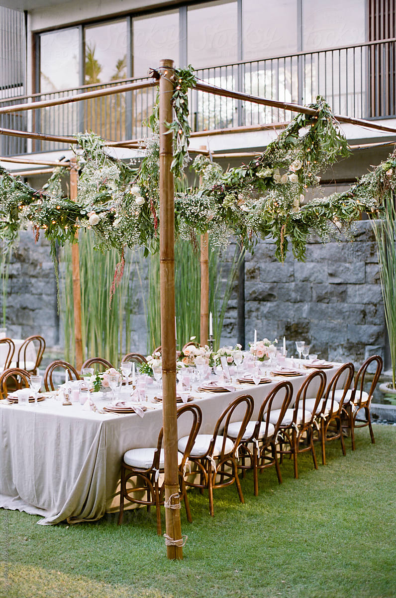 Outdoor, tropical wedding reception table with hanging greenery garlands