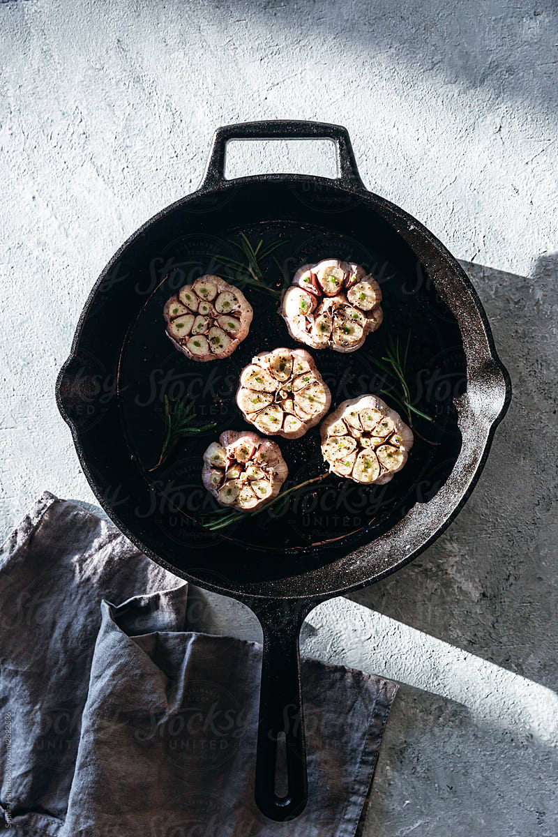 Garlic cloves with rosemary in cast iron