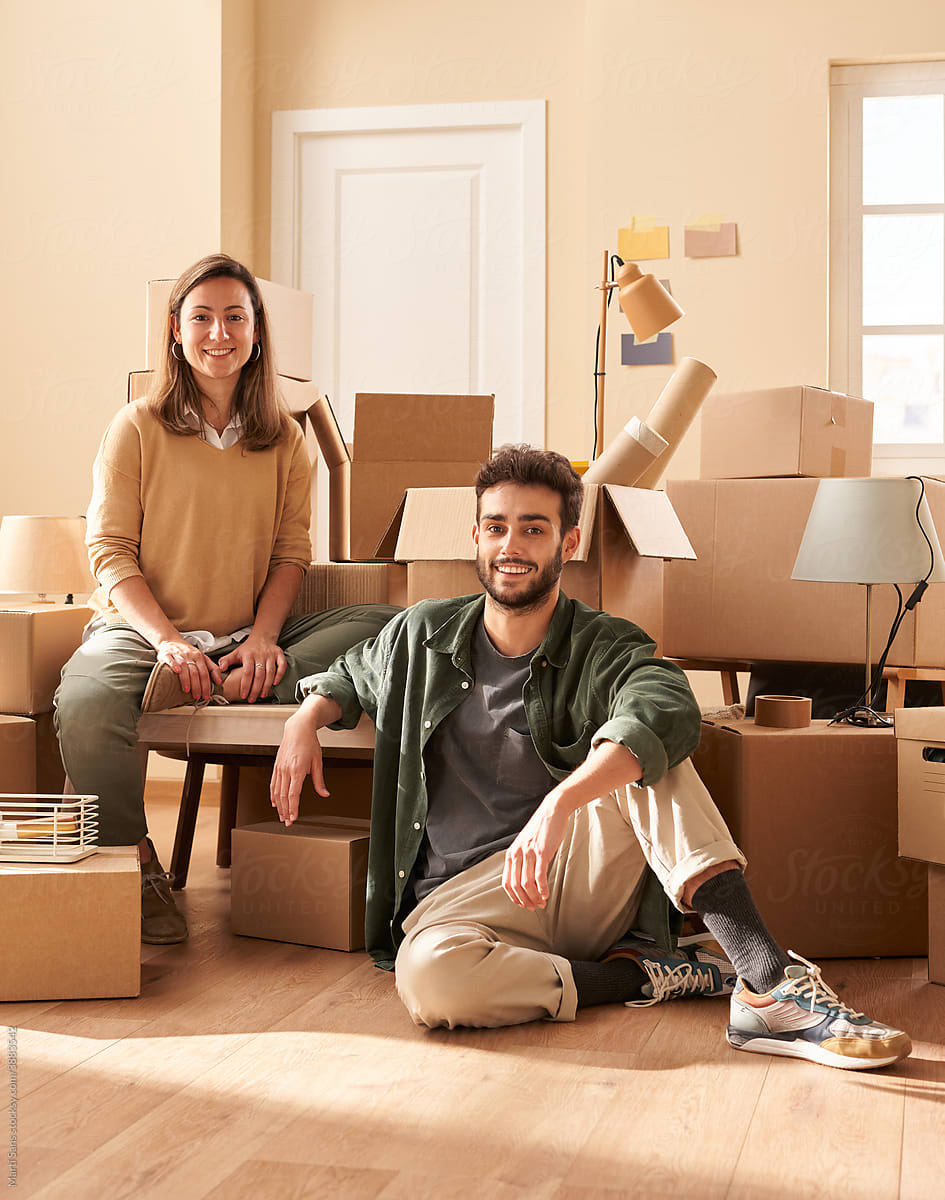 Optimistic man and woman near cardboard boxes during relocation
