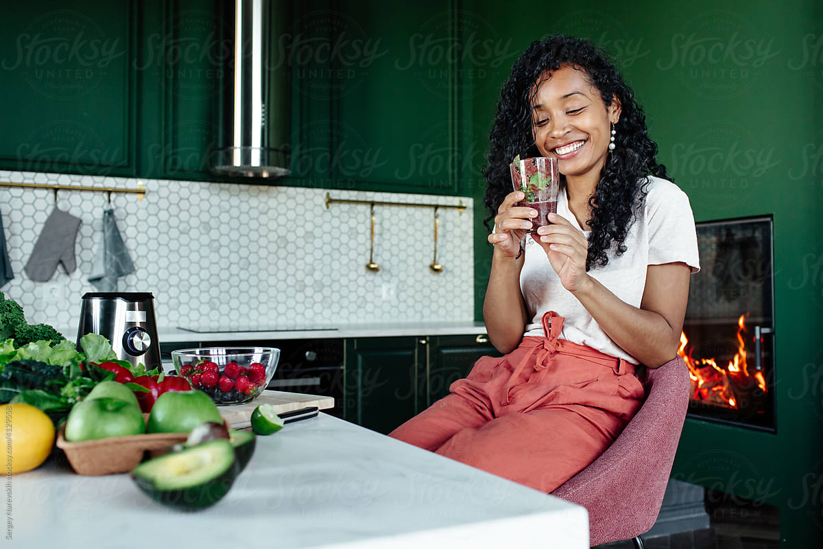 Cheerful black woman with glass of smoothie