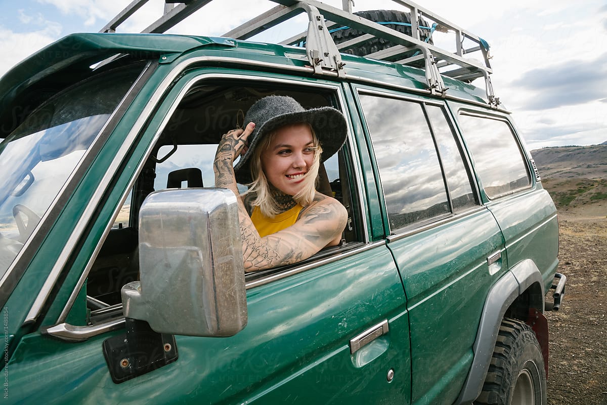 Young blonde tattooed woman sitting in the green car