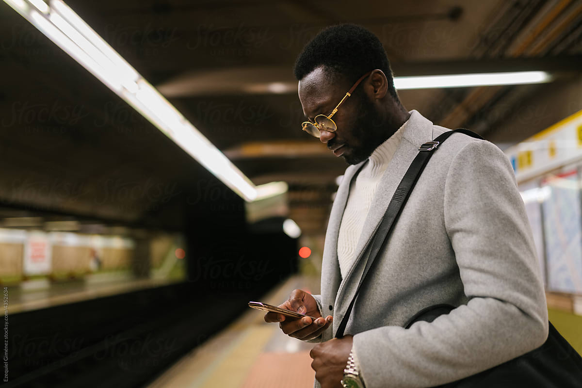 Black businessman browsing smartphone in subway
