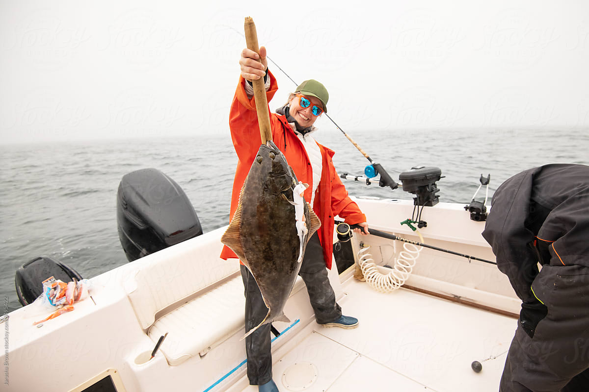 Woman holding a fresh halibut on a boat in the ocean