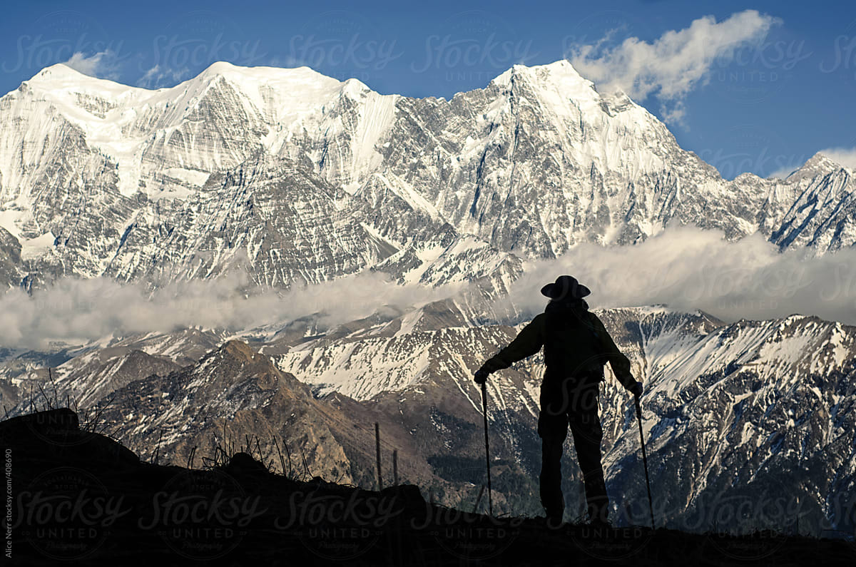 Trekker\'s silhouette in front of snowy Himalayas peaks