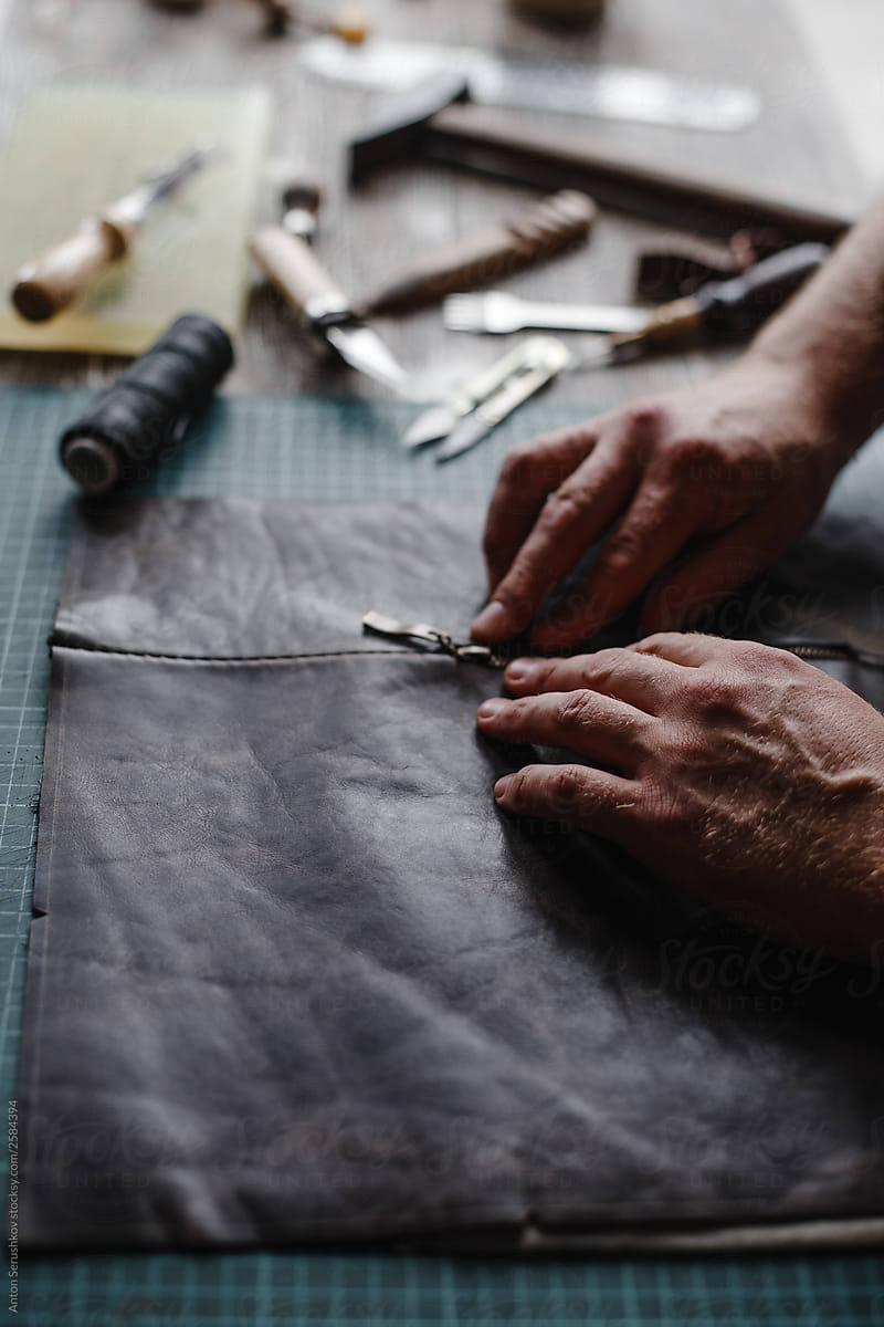 Detail of a handmade process: man makes a product (bag) from leather.