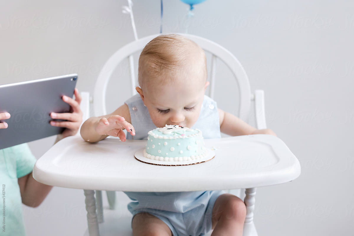 brother taking a video of baby eating his birthday cake