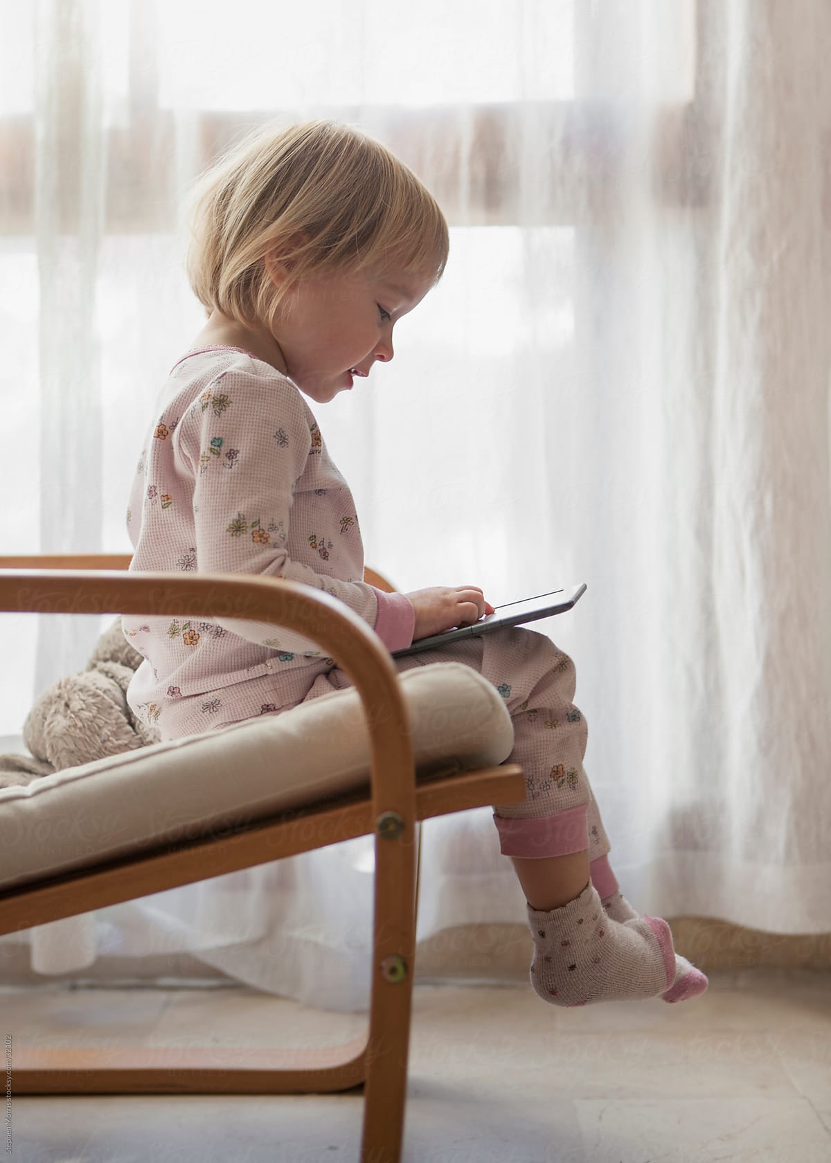 Little Girl Sitting Looking at Digital Tablet