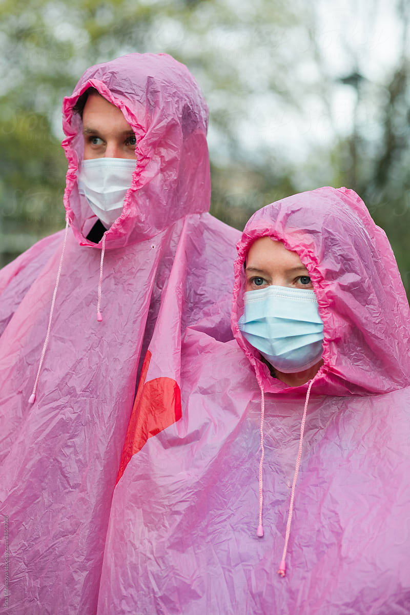 Pink raincoat covered couple wearing medical masks