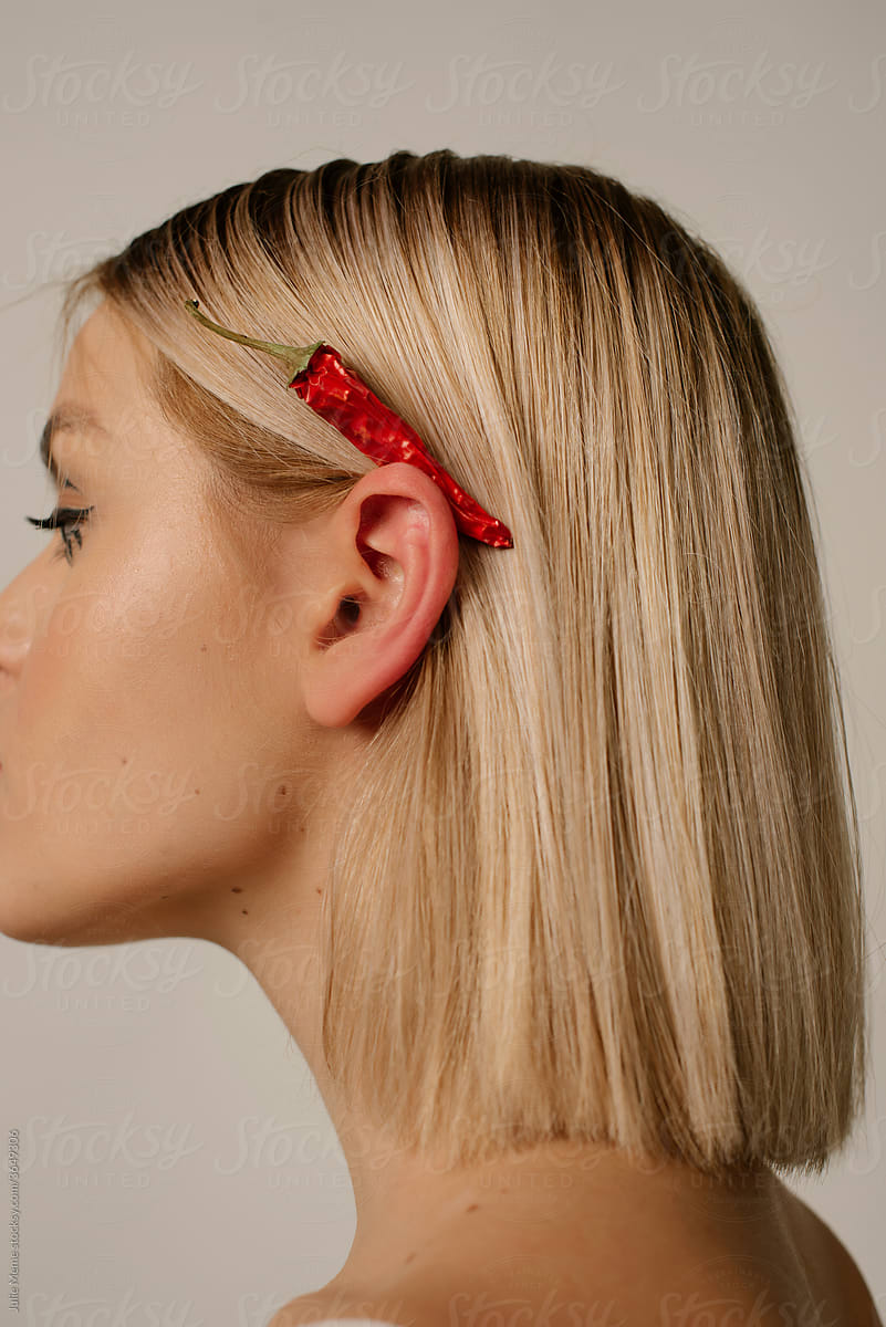 Profile View of Young blonde Woman With hot pepper